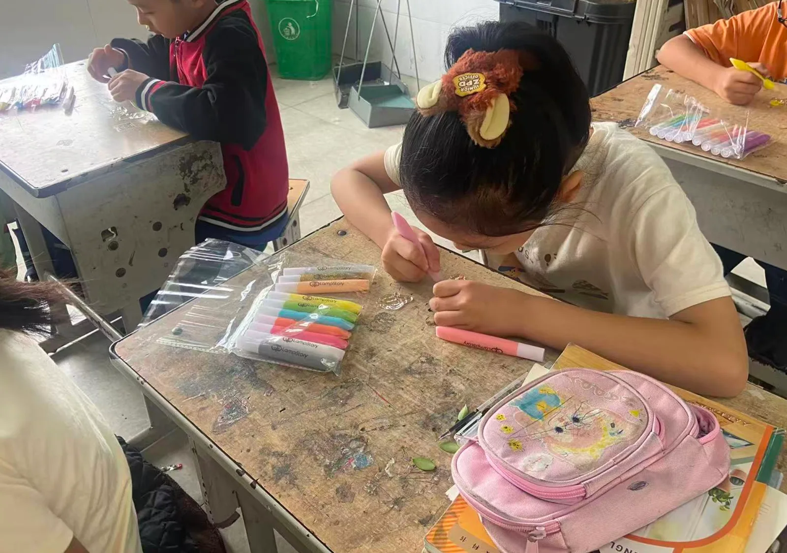 孩子握着粉色画笔，专注地为胶画上色
