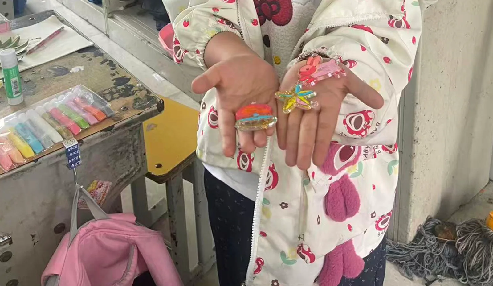 孩子张开双手，展示自己完成的彩色水彩胶画作品